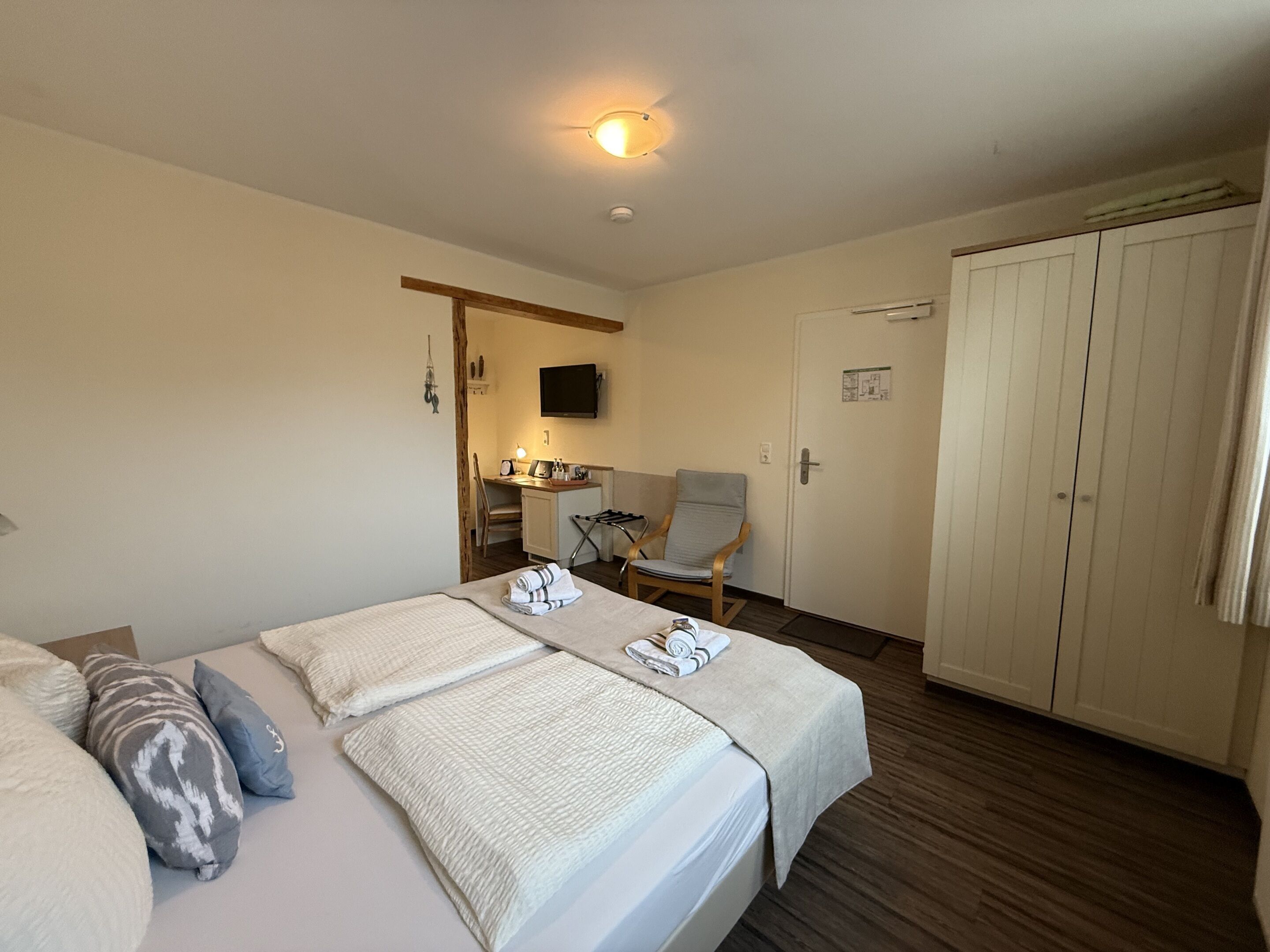Een hotelkamer met een bed, een bureau, een stoel en een kledingkast.