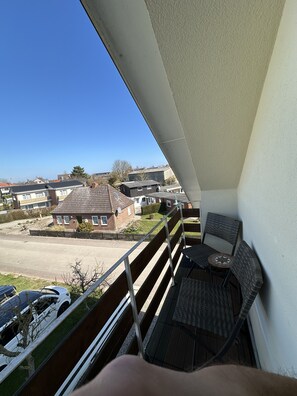A balcony with a view of a residential area, including houses and parked cars. - Pension Walmeer (Kellenhusen)