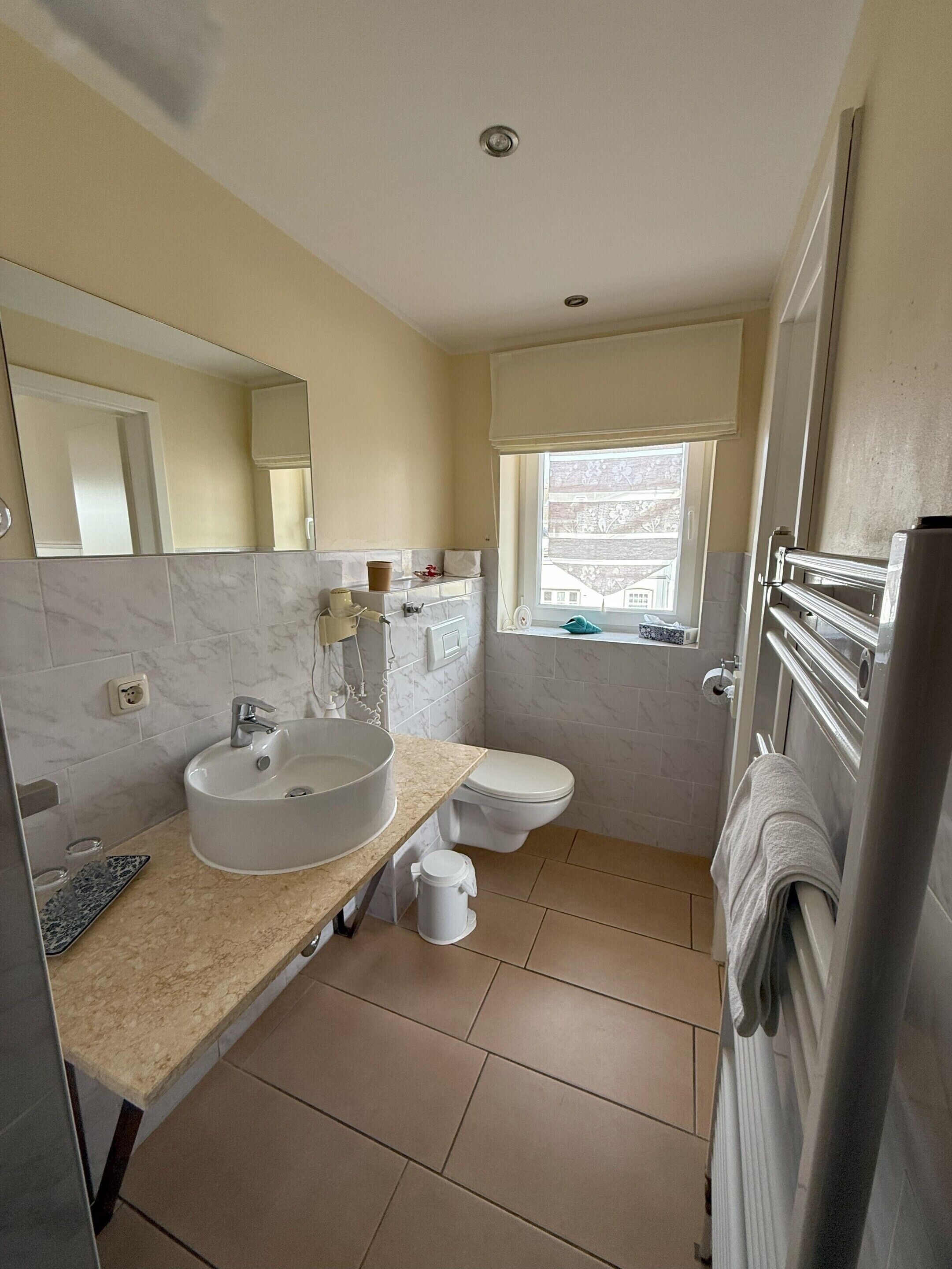 A modern bathroom with a sink, toilet, and a window.