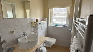 A modern bathroom with a sink, toilet, and a window.