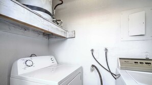 Una sala de bugaderia amb una rentadora de càrrega frontal i una combinació superposada de rentadora i assecadora.