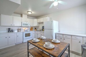 A modern kitchen with white cabinetry, a wooden dining table set with plates and glasses, and a ceiling fan. - Vegas Getaway Near Strip! Sleeps 6! (Las Vegas)