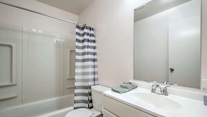Un bany amb banyera, vàter i un lavabo amb mirall.