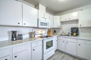 A modern kitchen with white cabinets, a built-in microwave, a coffee maker, and a toaster.