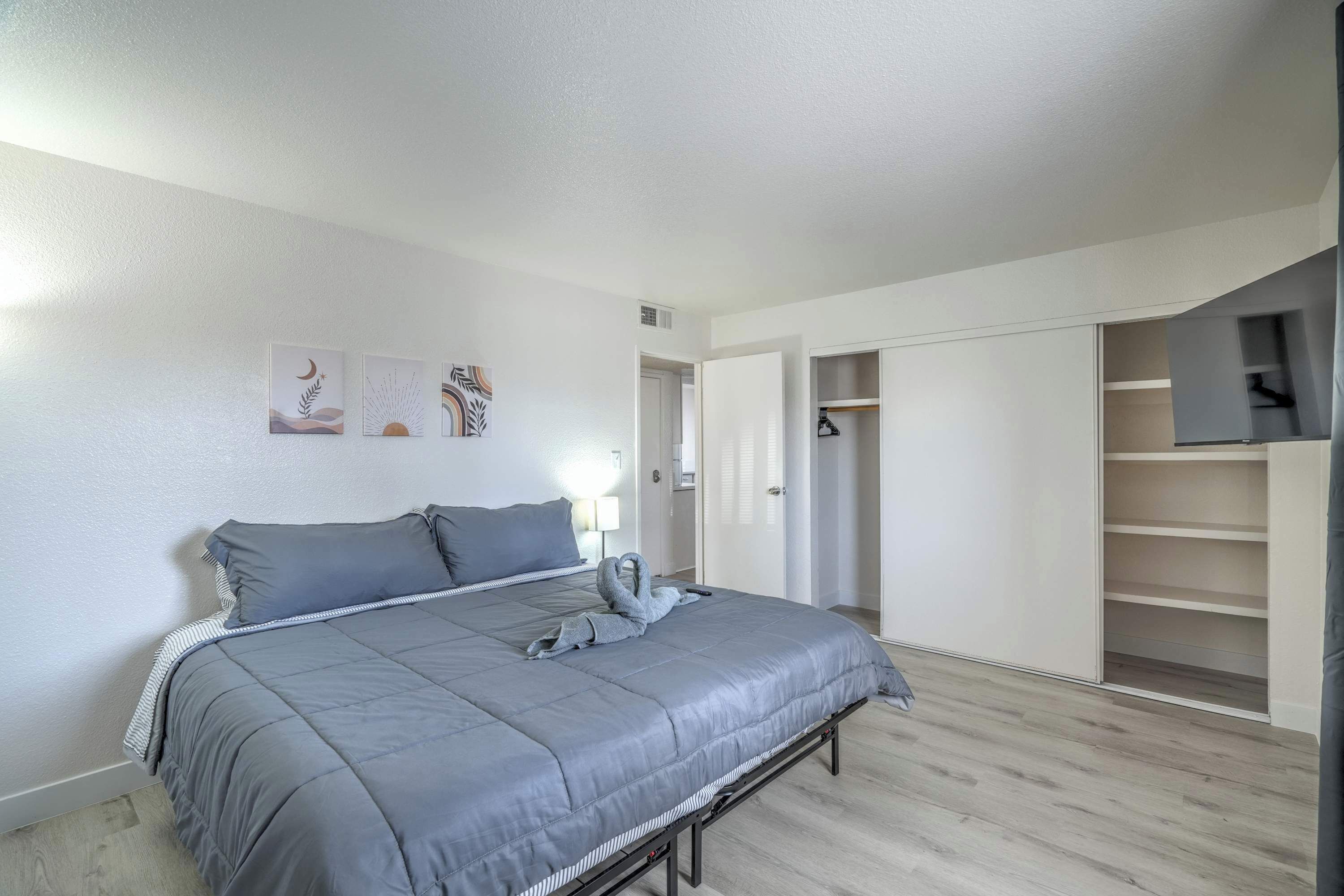A bedroom with a grey bed, a wardrobe, and a closet.