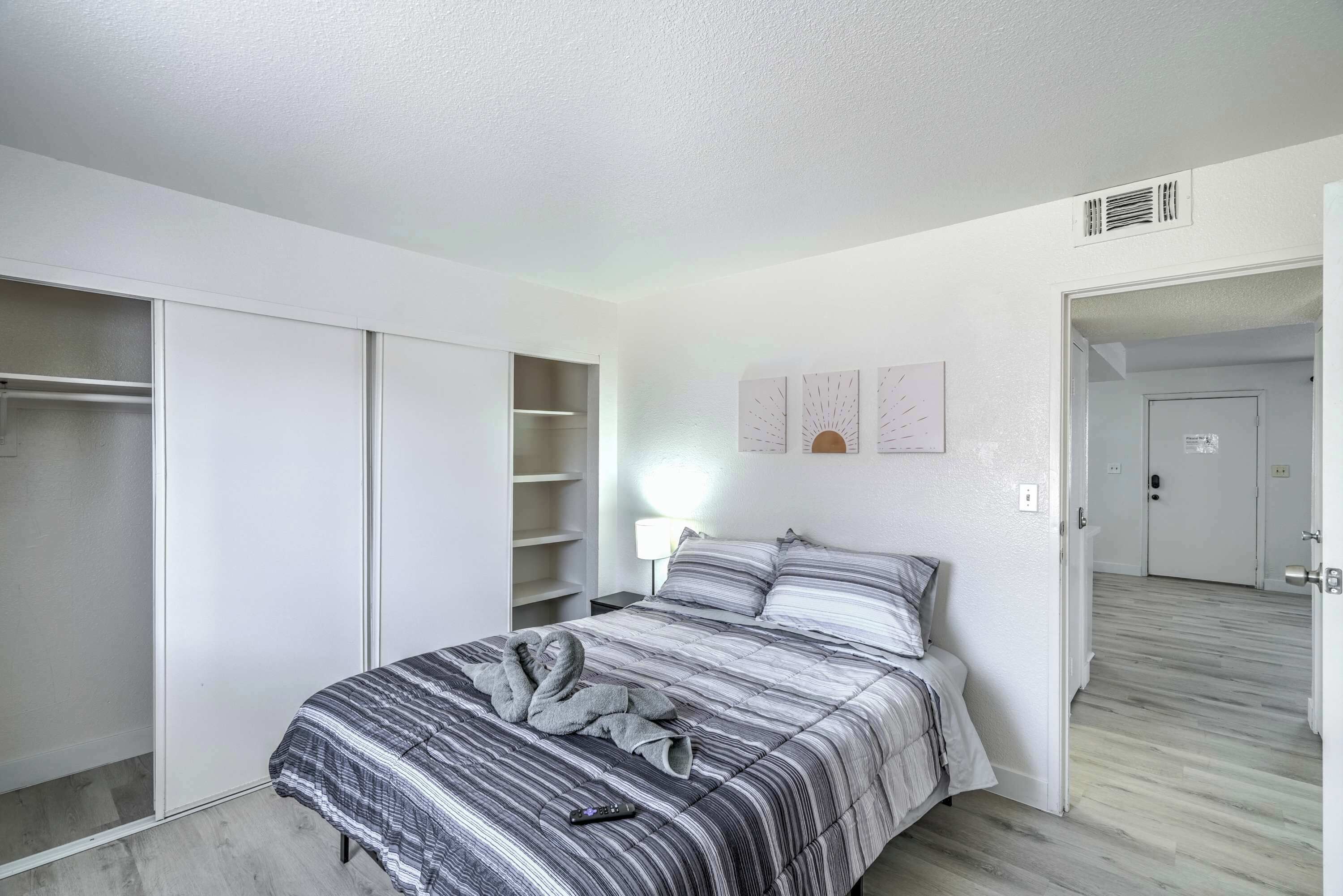 Une chambre à coucher comprenant un lit, une armoire, une table de chevet et une porte donnant sur une autre pièce.