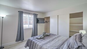 Un dormitori amb un llit, un armari, un televisor i una finestra amb cortines.