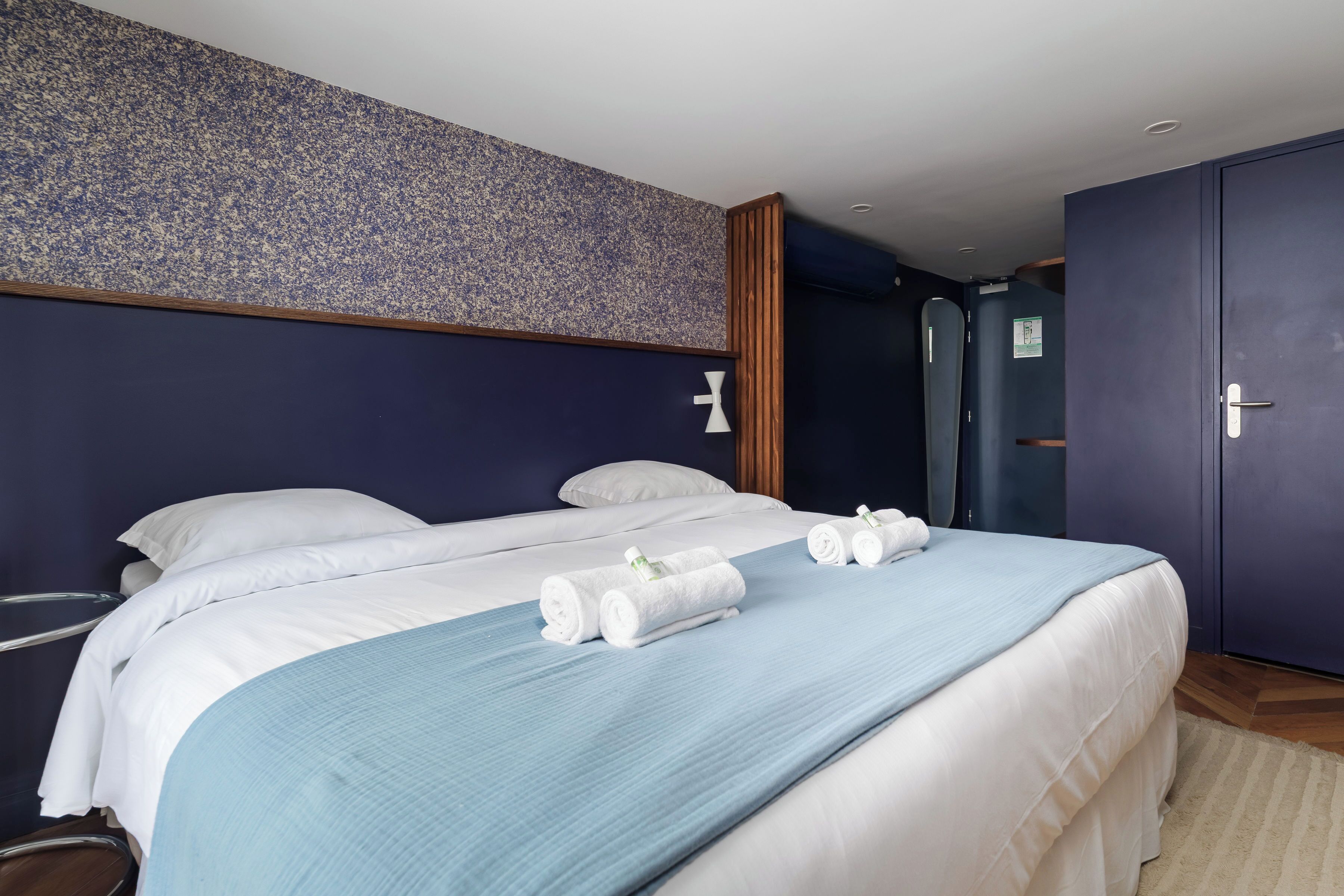 A hotel room with two beds, a large window, and a door to the bathroom.
