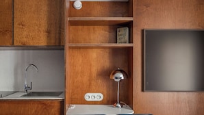 Eine moderne Küche mit Holzschr änken, einer integrierten Spüle, einer weißen Arbeitsplatte, einem Schreibtisch mit Lampe und zwei blauen Stühlen.