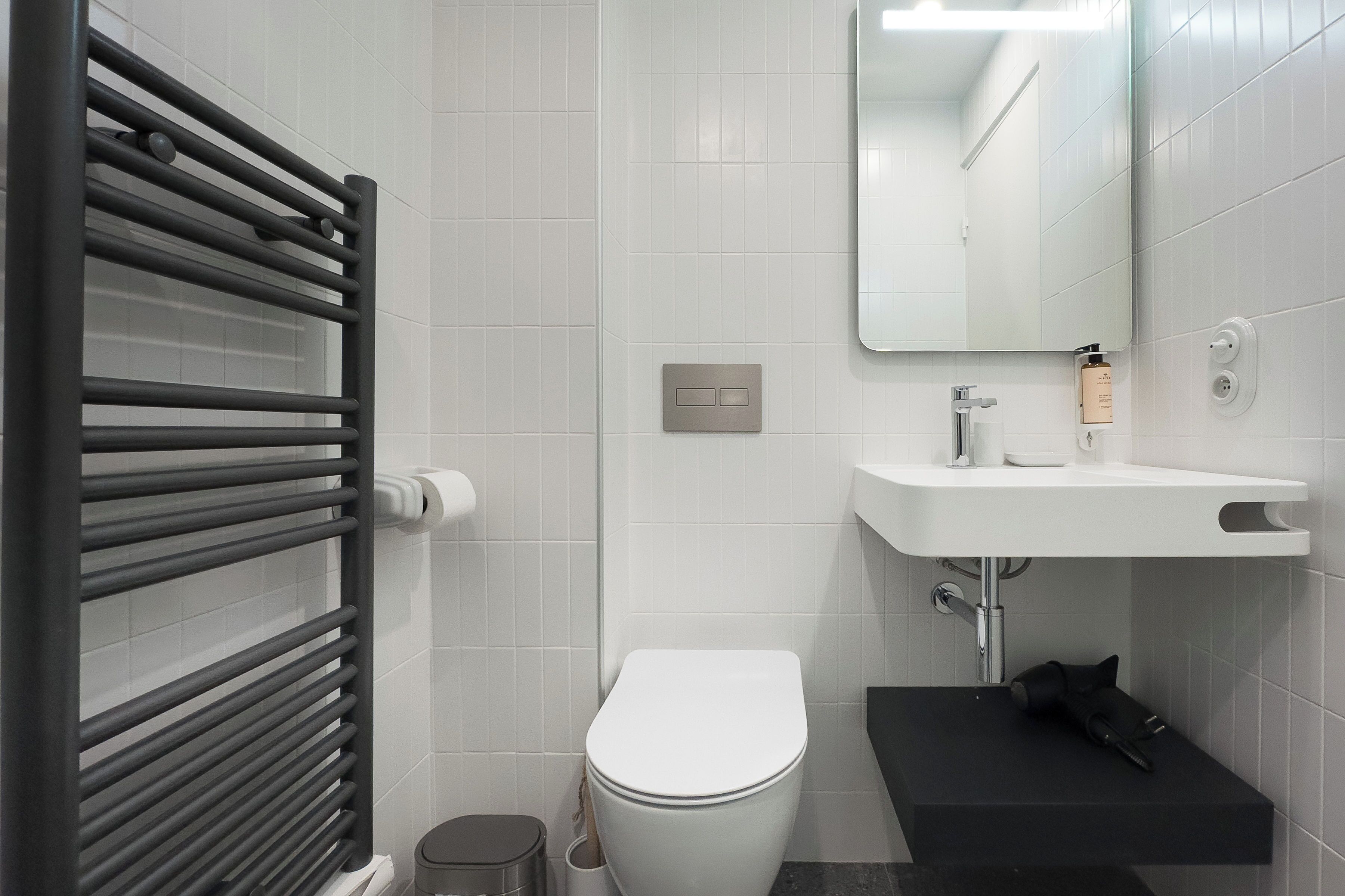 A modern bathroom with a white toilet, a black sink, and a towel rack.