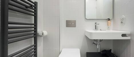 A modern bathroom with a white toilet, a black sink, and a towel rack.