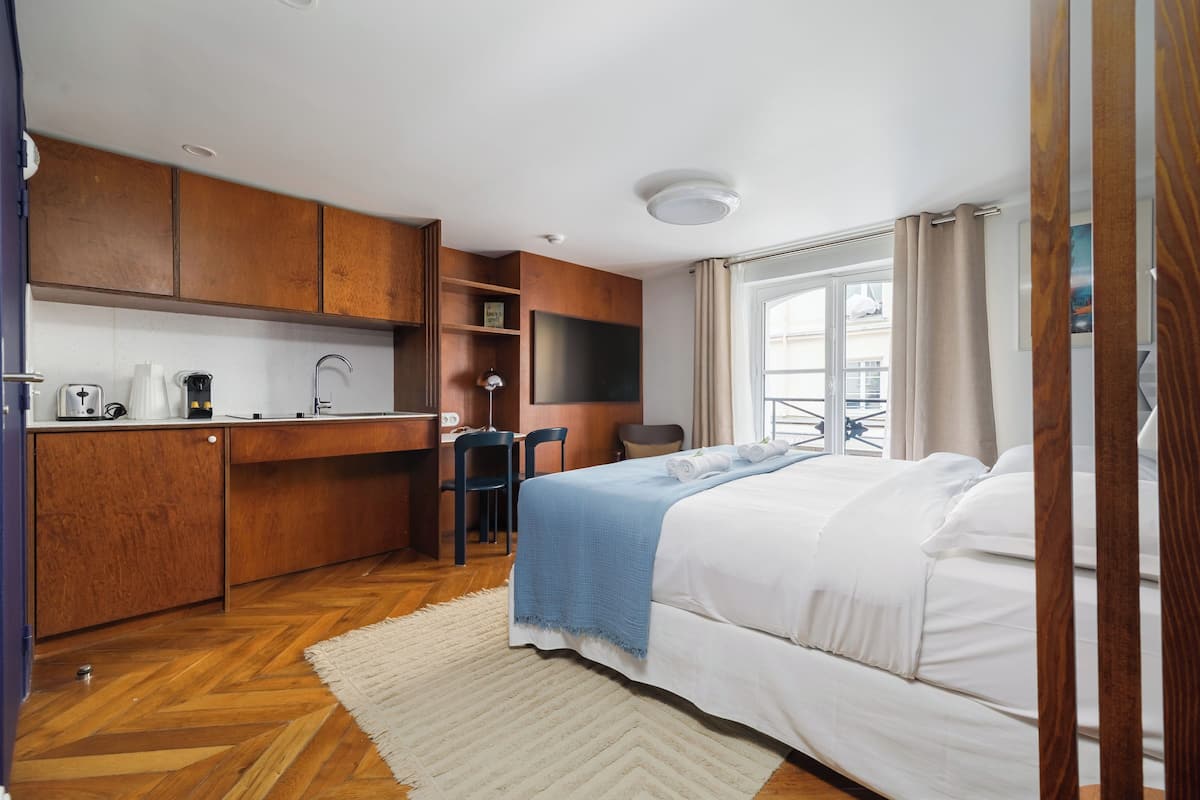 Una habitación de hotel compacta con kitchenette, una cama, un escritorio y una silla.