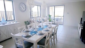 A dining area with a white table set for six, surrounded by white chairs. - Eglinton Elegance - Hamptons Retreat (Eglinton)