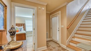 A hallway with a wooden staircase, a bed with a headboard, and a door with a window. - Dog Friendly! 5 bedroom, 3 bath house near the MarshWalk (Murrells Inlet)