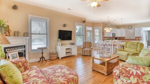 A spacious living room with a fireplace, a television, and a dining area with chairs. - Dog Friendly! 5 bedroom, 3 bath house near the MarshWalk (Murrells Inlet)