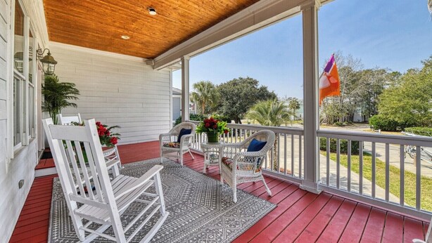 A covered porch with white wicker chairs, a small table, and a flag. - Dog Friendly! 5 bedroom, 3 bath house near the MarshWalk (Murrells Inlet)