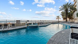 A pool area with a hot tub, lounge chairs, and palm trees. - Admiral Quarters Luxury Condo Gulf Front - Remodel (Orange Beach)