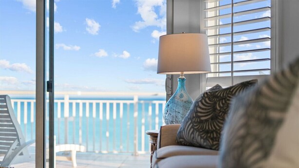 A balcony with a view of the sea, a sofa with patterned cushions, and a lamp. - Admiral Quarters Luxury Condo Gulf Front - Remodel (Orange Beach)