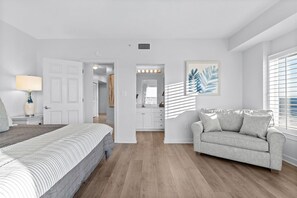 Relax in a serene bedroom with a large bed, vanity, and sofa.