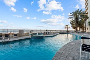 Relax by the pool surrounded by palm trees and lounge chairs.