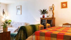 Un cuarto acogedor con cama, sofá, mesa de comedor con sillas, aparador con adornos y una planta en maceta.