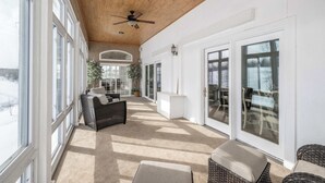 A spacious covered patio with large windows, a ceiling fan, and wicker furniture. - The Bishops Manor, Stay for 10! (West Chester)