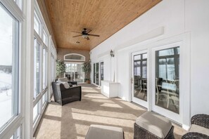 A spacious indoor area with large windows, a ceiling fan, and a view of the outdoors. - The Bishops Manor, Stay for 10! (West Chester)