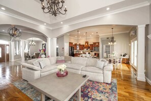 A spacious living room with a large sectional sofa, a coffee table, and a chandelier. - The Bishops Manor, Stay for 10! (West Chester)
