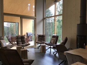 A spacious room with large windows, a fireplace, and comfortable seating. - Havu Resort (Jyväskylä)