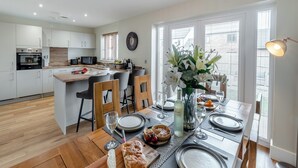 A modern kitchen with white cabinets, a central island, and a dining area with a table set for four.