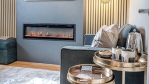A modern living room with a fireplace, a sofa, a tray with mugs and a kettle, and a painting on the wall.
