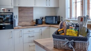A kitchen with white cabinets, a microwave, and a wicker basket with food items on the counter.