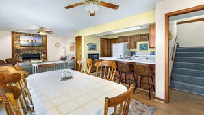A spacious dining area with a large table and chairs, a kitchen with modern appliances, and a ceiling fan. - Sunset Escape - Fit For 8! (Gravois Mills)