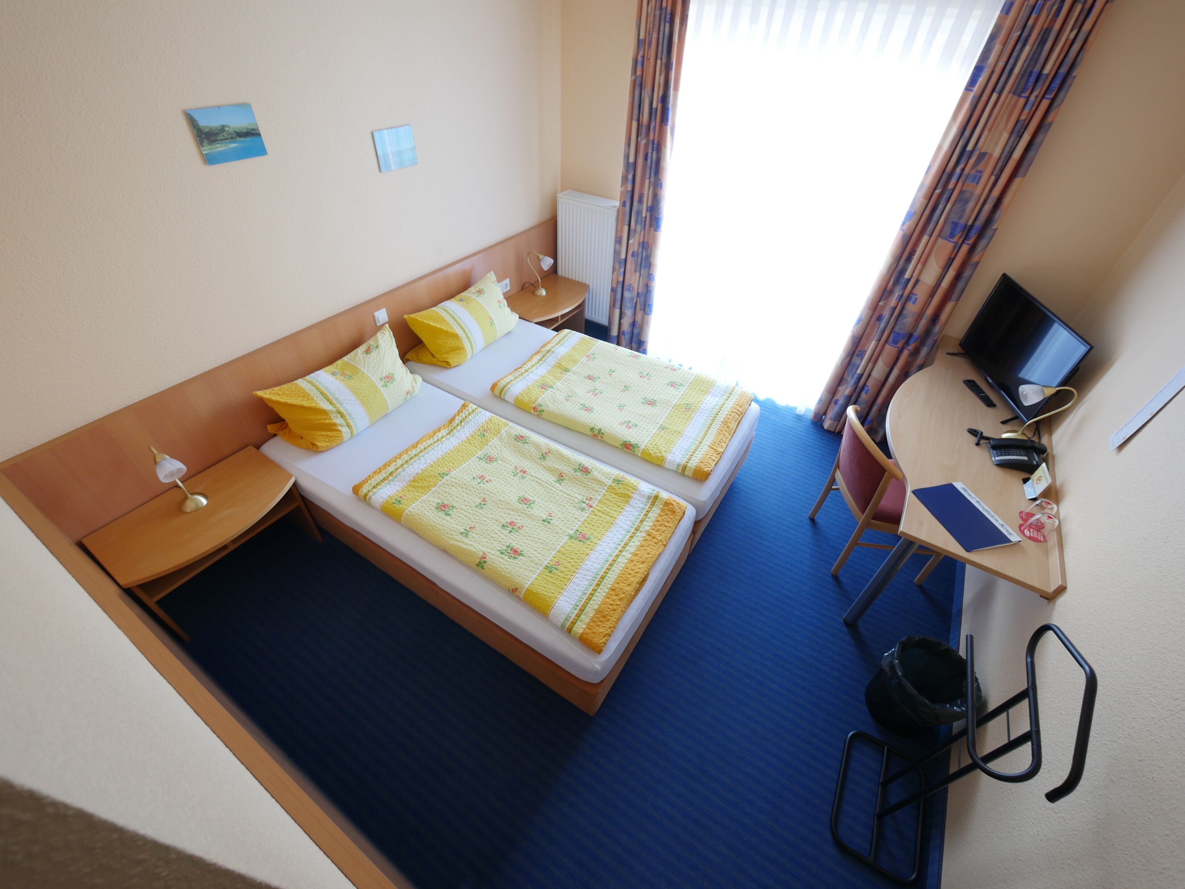 A hotel room with two beds, a desk with a computer, and a chair.