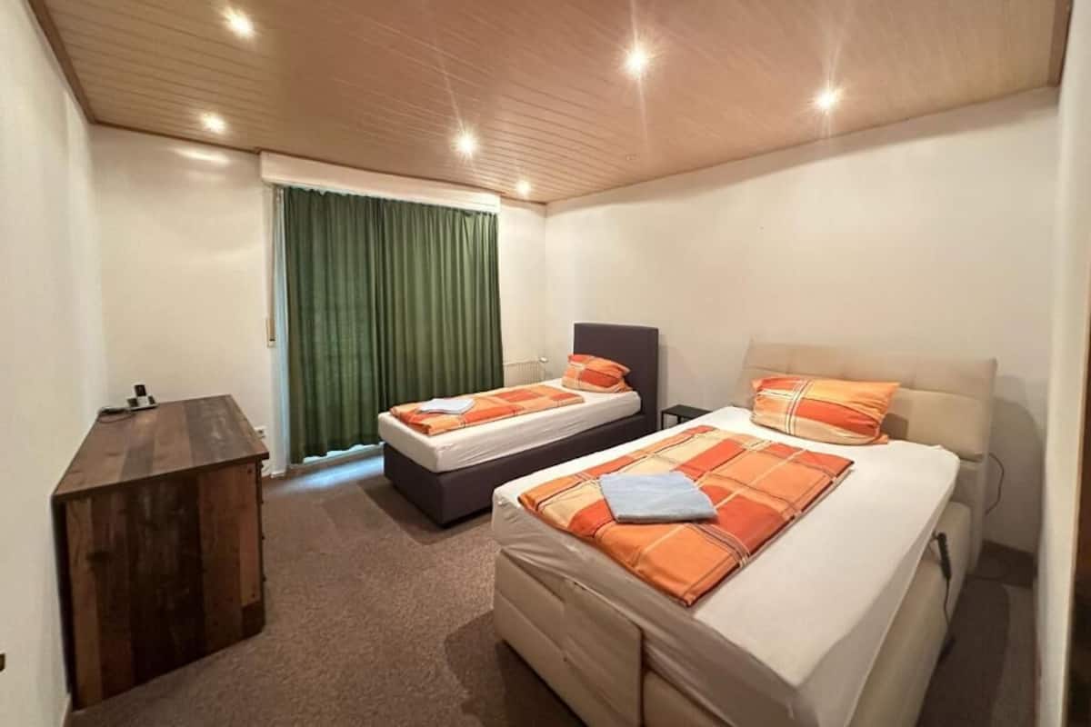 Een hotelkamer met twee bedden, een bureau en een groot raam met gordijnen.