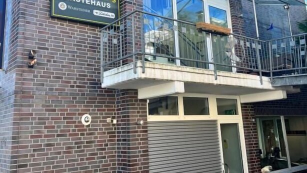 Een gebouw met twee verdiepingen, een gevel van baksteen, een balkon met glazen hekwerk en een bord dat restaurant 'Westfalen-Ring GÄSTEHAUS' aangeeft.