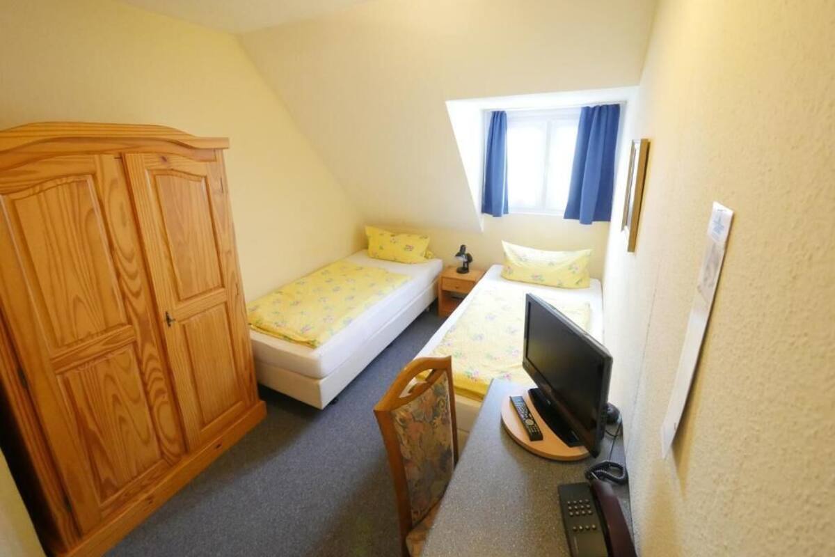 Een slaapkamer met een bed, een bureau met een computer, een televisie en een kledingkast.