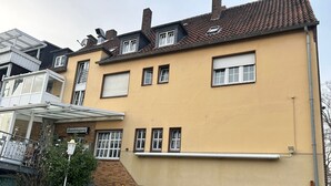 Een meerlaags hotel met een geel gevel, meerdere ramen en een zichtbare trap die naar de ingang leidt.