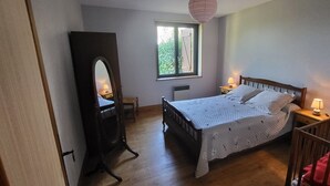 A bedroom with a bed, a wooden dresser, a mirror, a window, and a crib. - LA CROIX..... Beautiful Périgourdine house (Saint-Genies)