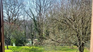 A view from inside a room with a window overlooking a grassy area with trees and a distant building. - LA CROIX..... Beautiful Périgourdine house (Saint-Genies)