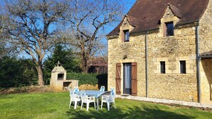 A stone building with a traditional design, a small outdoor seating area with white chairs, and a clear sky. - LA CROIX..... Beautiful Périgourdine house (Saint-Genies)