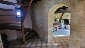 A stone-walled interior with a wooden staircase, a stone fireplace, and a sofa in the background. - LA CROIX..... Beautiful Périgourdine house (Saint-Genies)