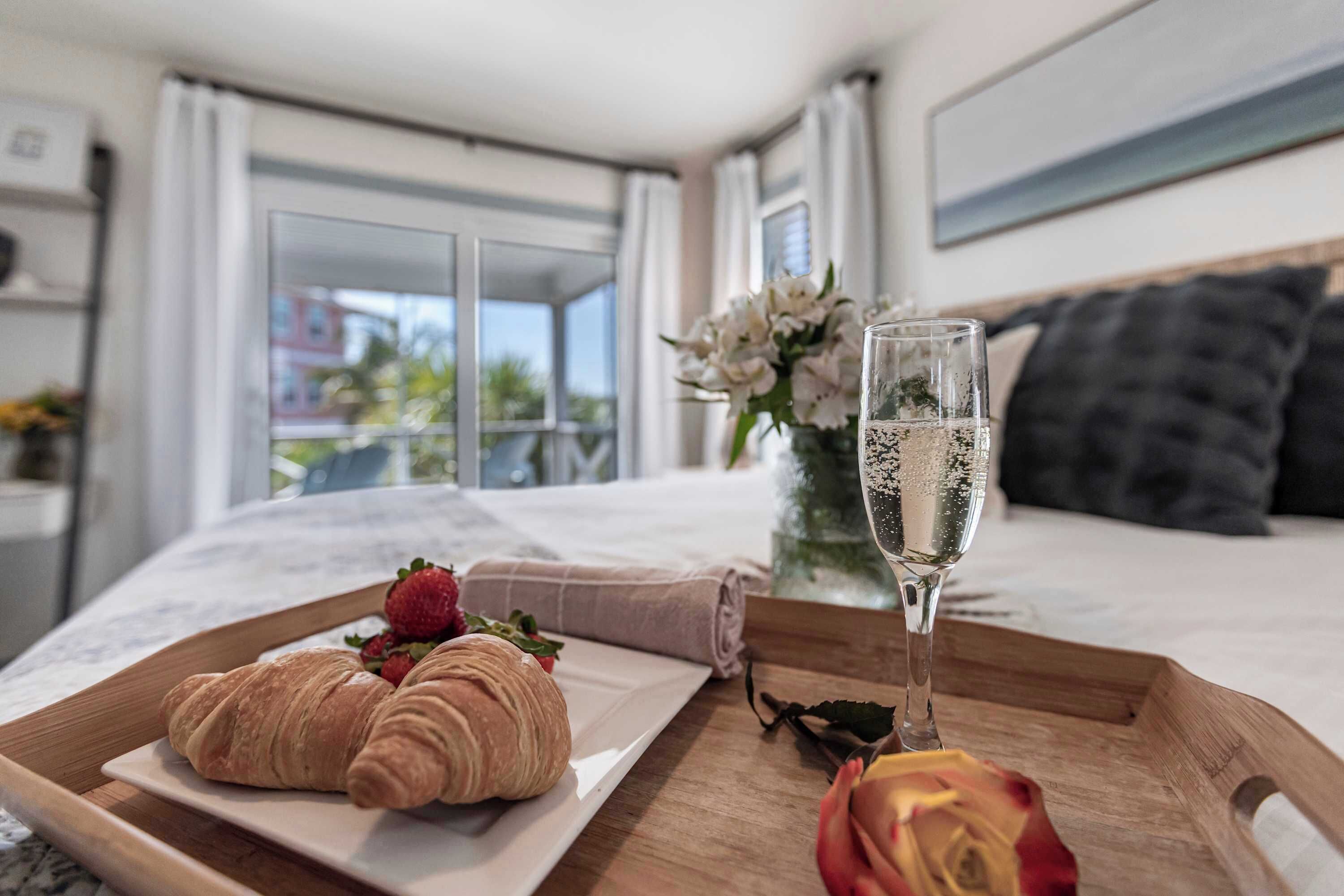 Ein Schlafzimmer mit einem Bett, einem Tablett mit Croissants und einem Glas Wasser sowie einer Vase mit Blumen.