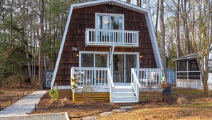 A cabin with a two-story balcony, a front door, and a number '34' on the side. - Ocean Pines 2BR 1BA Cottage with Fire Pit (Ocean Pines)
