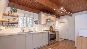 A modern kitchen with wooden beams, a large island, and a built-in oven. - Ocean Pines 2BR 1BA Cottage with Fire Pit (Ocean Pines)