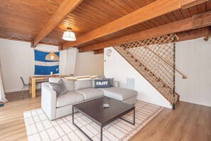 Uma sala de estar aconchegante com um sofá, mesa de centro e escada com guarda-corpo de rede.