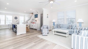 A spacious living area with a kitchen, a staircase, and a ceiling fan. - New Townhome Steps from the Beach (Ocean City)