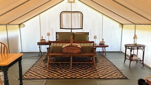 A tent with a bed, a table, and a chair. - Peaceful, Private 1-bedroom campground in Vandalia (Vandalia)