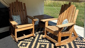 A tented outdoor seating area with two wooden chairs and a table, a patterned rug, and a view of a grassy field. - Peaceful, Private 1-bedroom campground in Vandalia (Vandalia)
