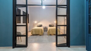 Quarto com duas camas, uma mesinha e uma cadeira.